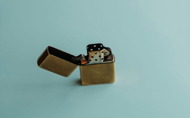 brass zippo-style lighter with its lid open and two dice resting on its top surface